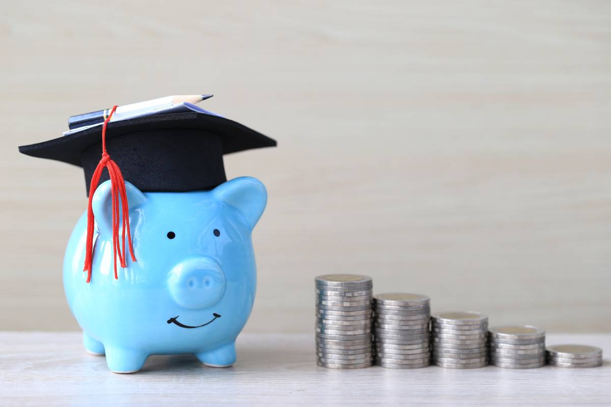 A blue piggy bank wears graduate’s mortar hat next to stacked coins near Richmond, Kentucky (KY)