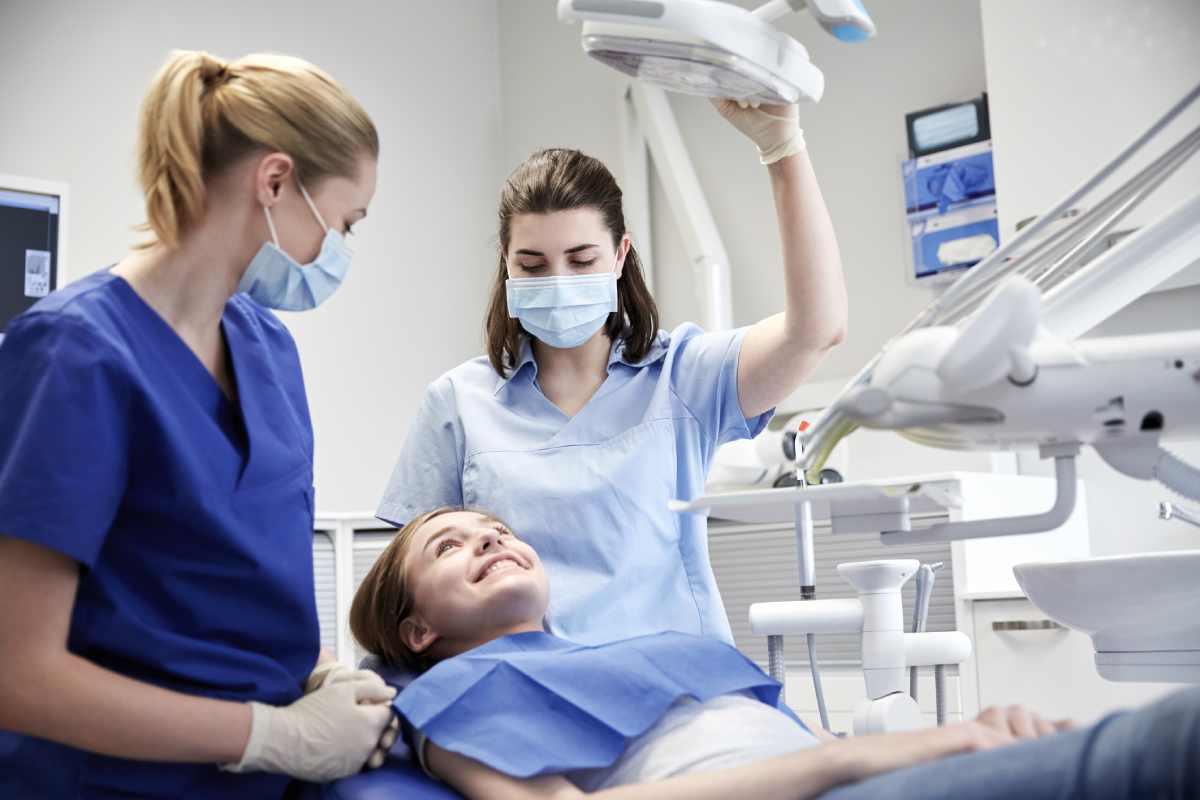 A dental assistant helping a dentist and patient near Lexington, Kentucky (KY)