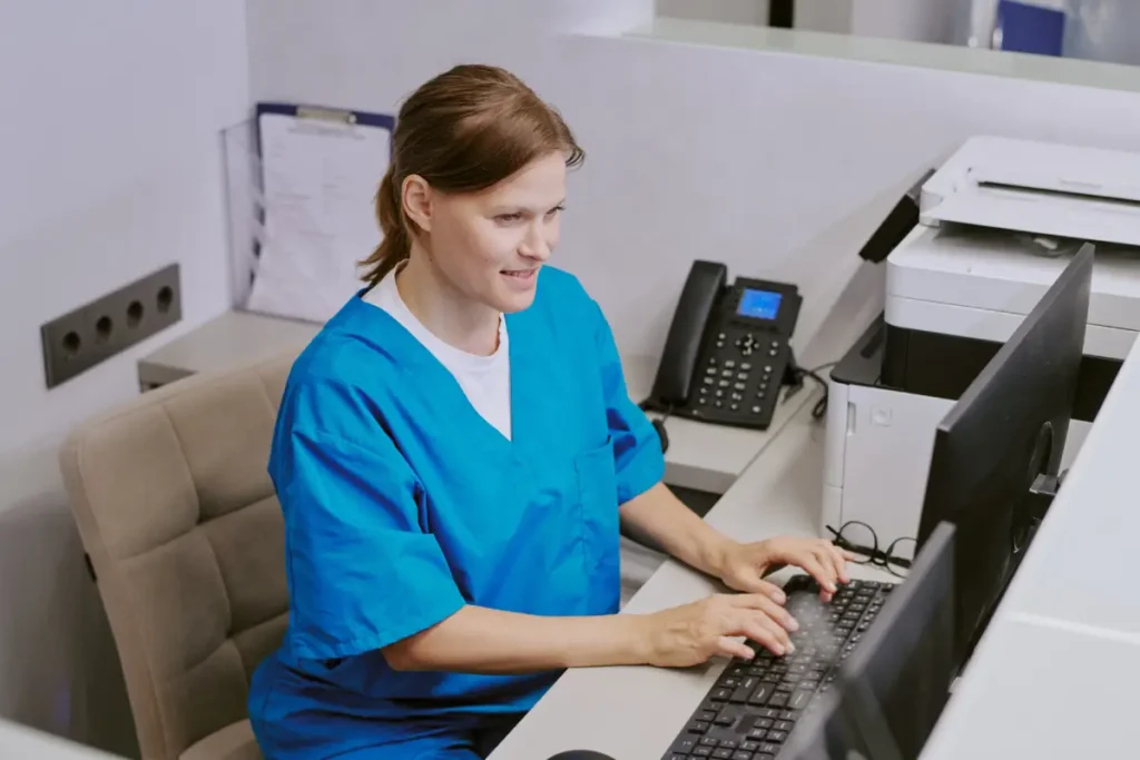 Medical billing and coding specialist entering data on a computer in a healthcare office.